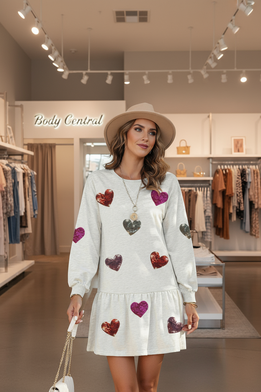 A Woman wearing a white dress with heart patterns in a Body Central clothing store.